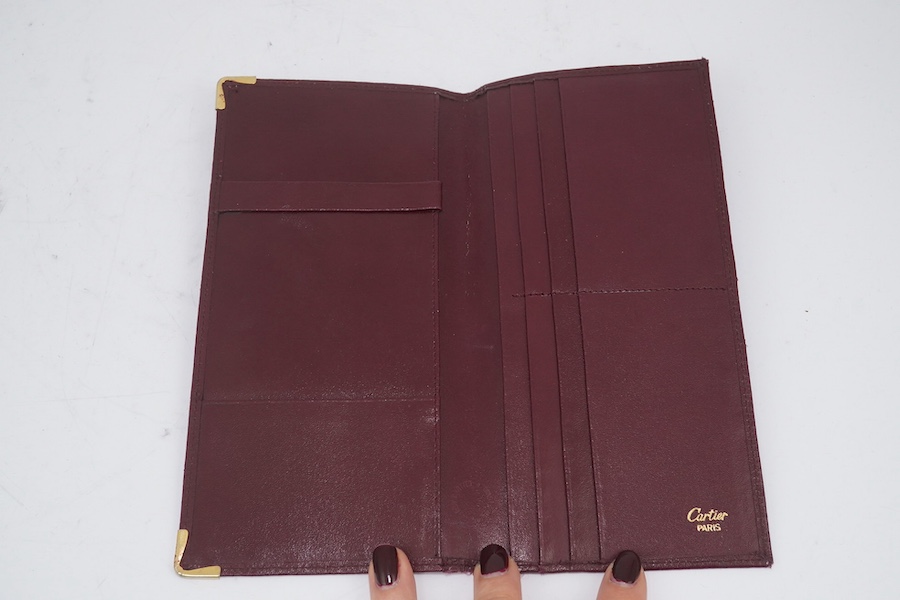 An assortment of Must de Cartier bordeaux leather accessories